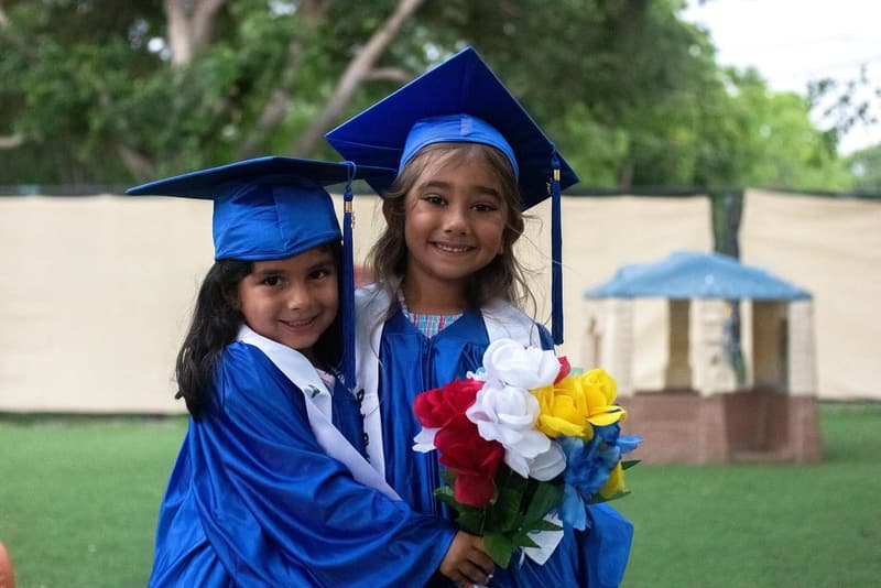 Two VPK graduates hugging in caps and gowns