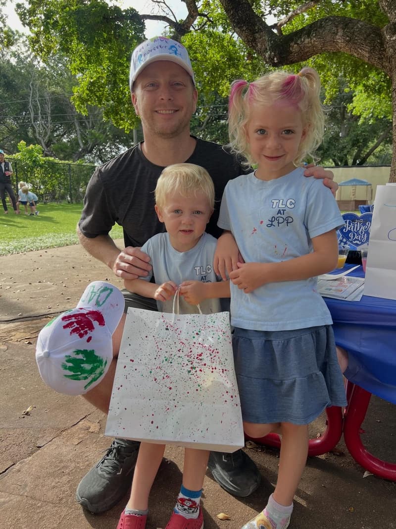 A dad with his two children holding handprint art bags