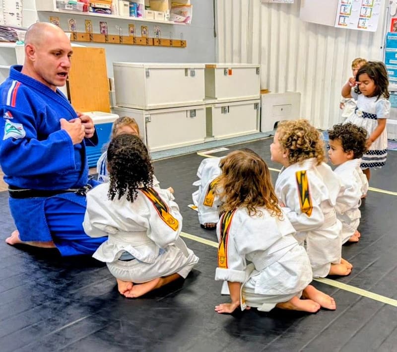 Students kneeling on the mat listening to their judo coach