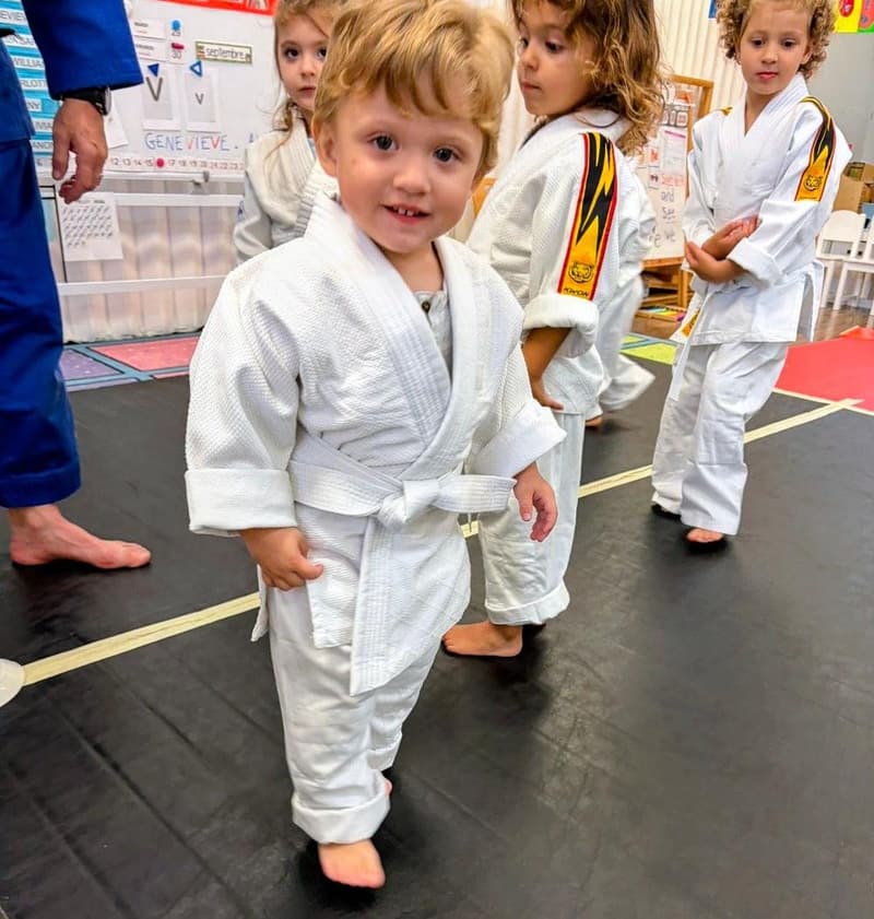 A young student smiling in his judo uniform