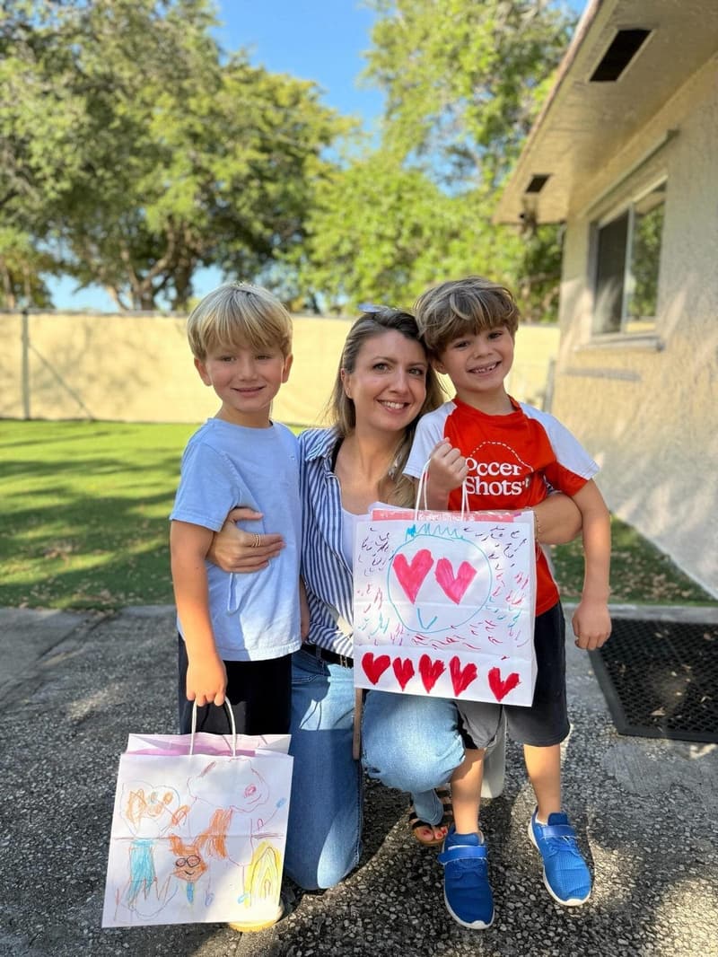 A mom with her two sons holding their art bags