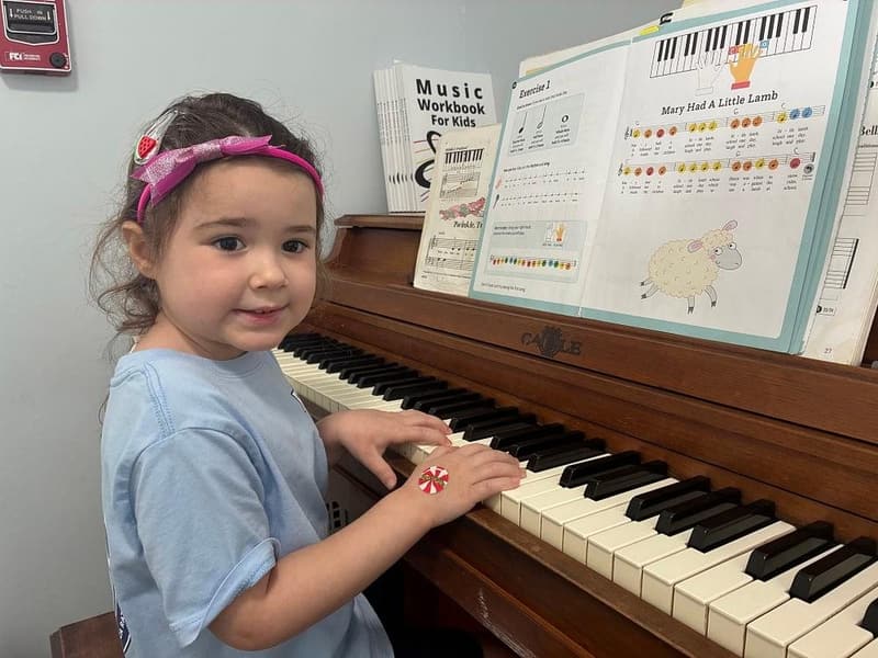A student smiling at the piano during a music lesson