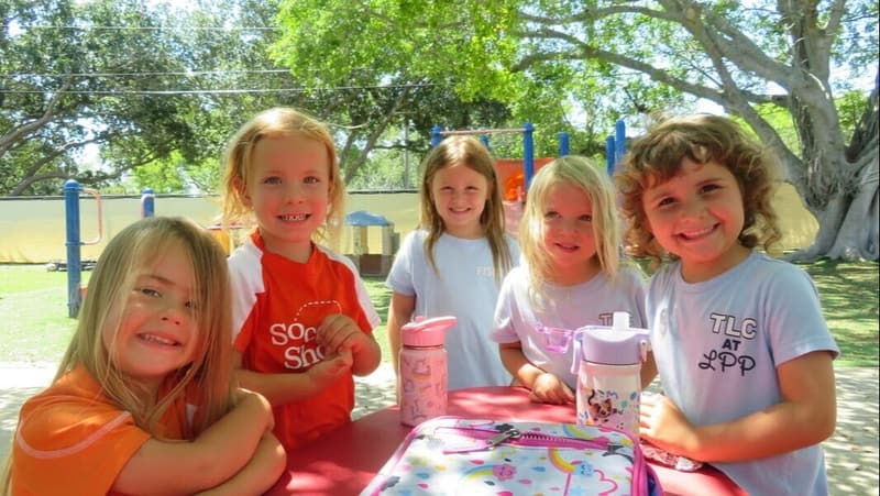 Five smiling students at a picnic table outdoors