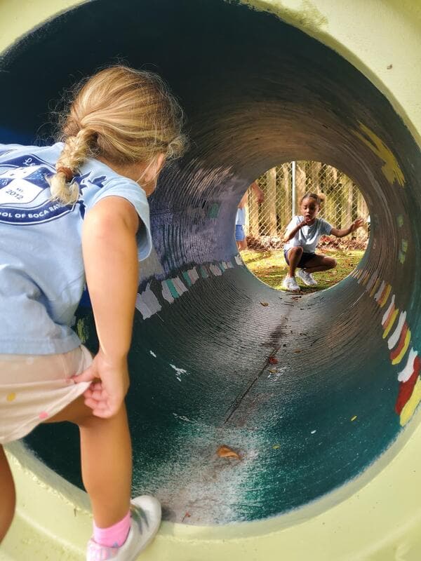 A student crawling through a play tunnel