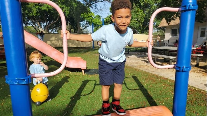 A student smiling on the playground climbing structure