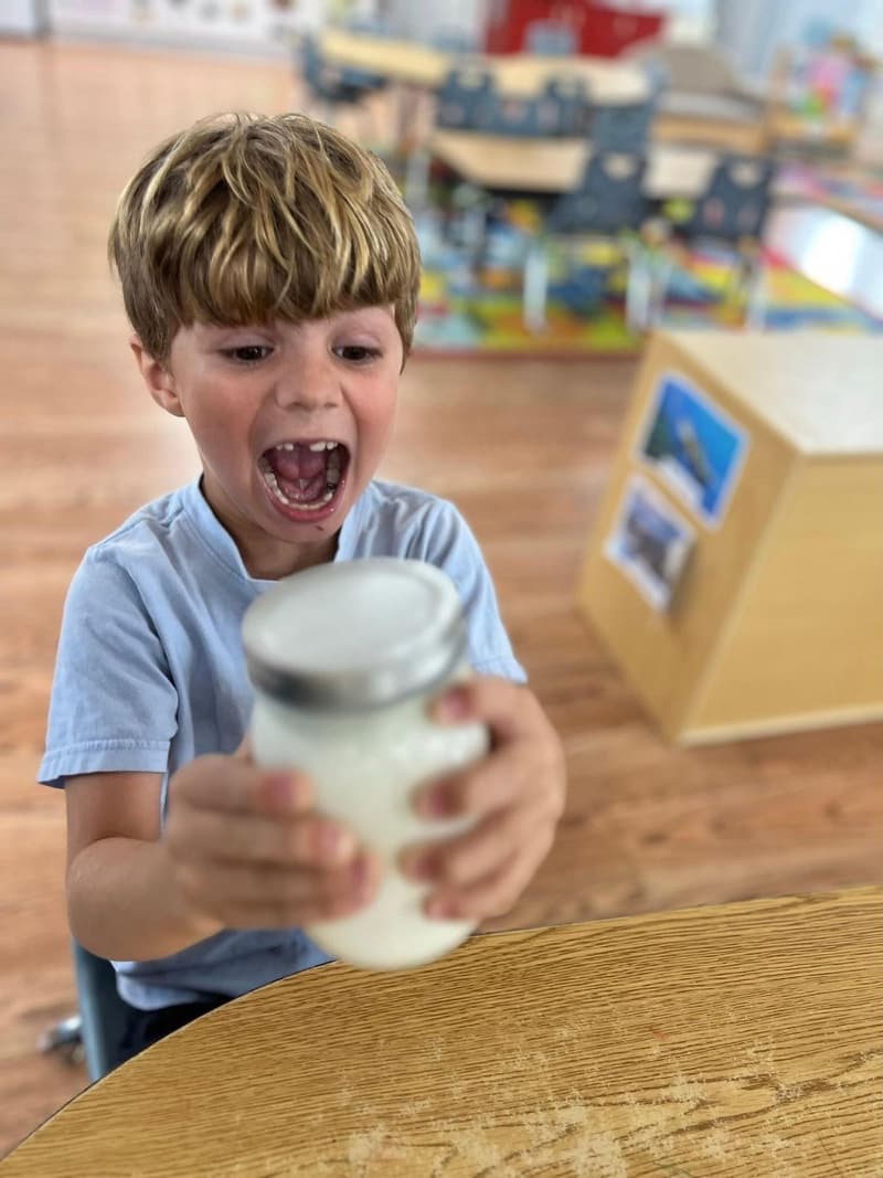 A student excitedly holding a jar during a science activity