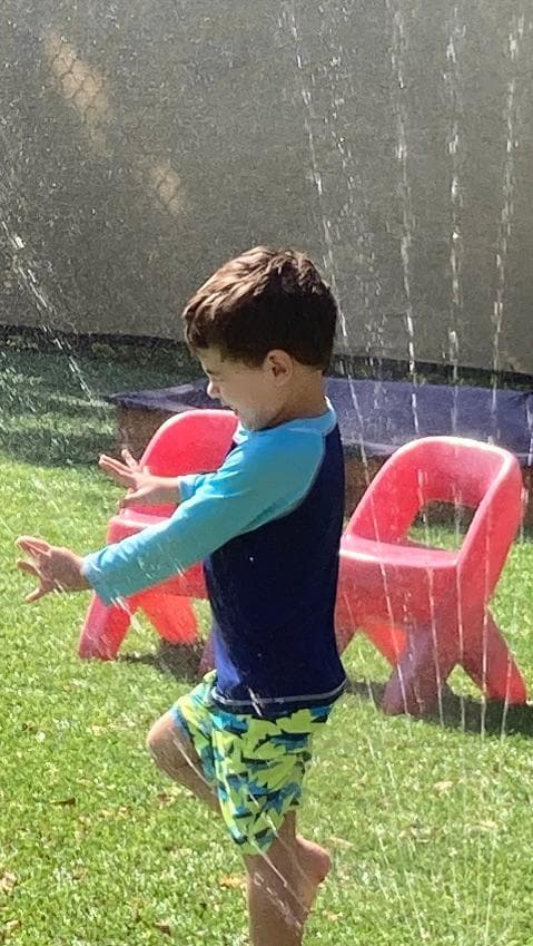 A student running through a sprinkler
