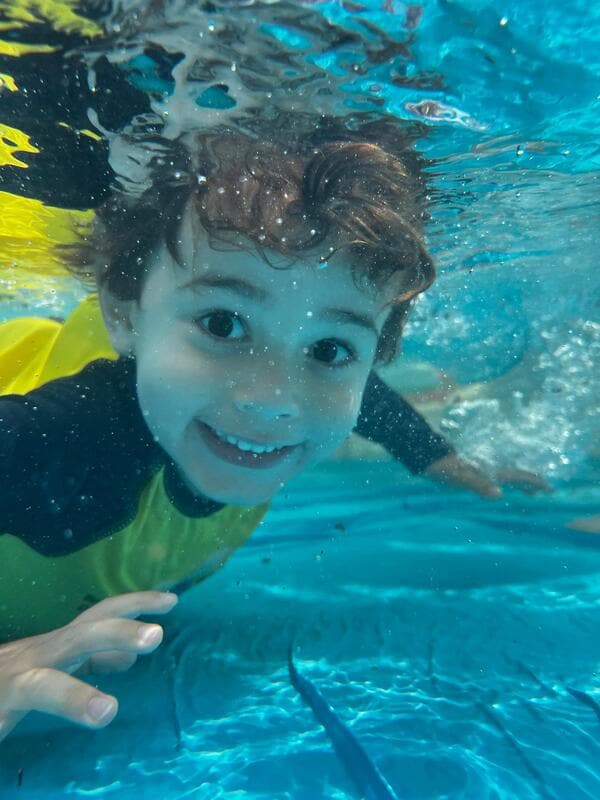 A student swimming underwater at summer camp