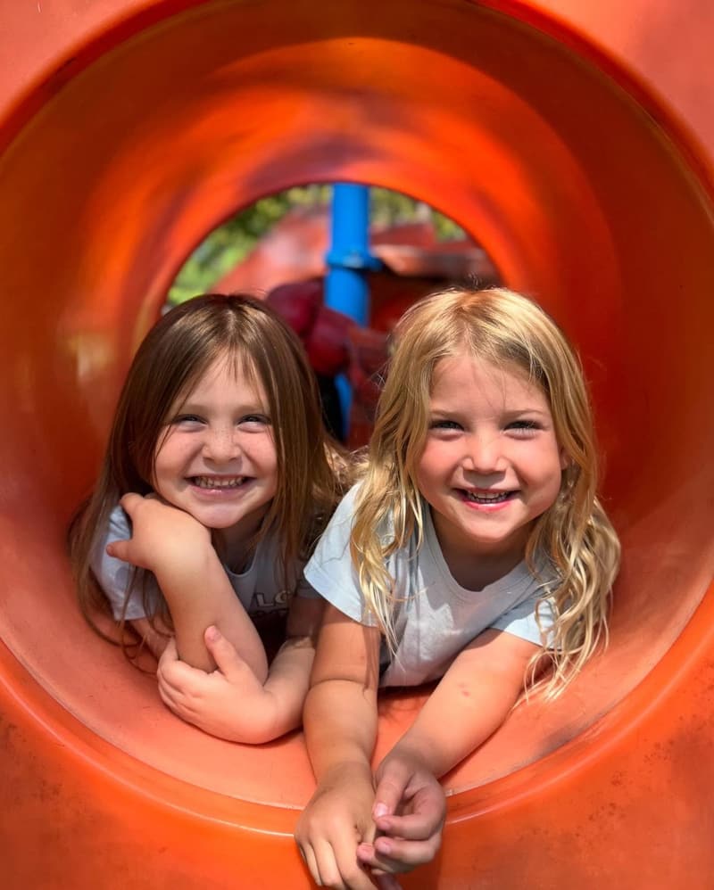 Two students smiling inside a play tunnel